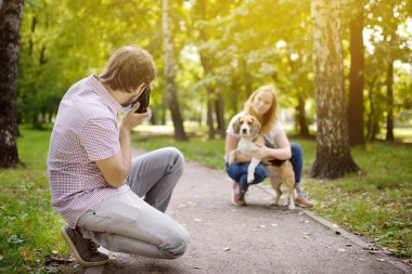 Genç adam güneşli yaz parkında köpek ile güzel bir kadın bir çekim almak. Tarih veya yürüyüş.