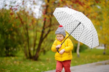 Küçük çocuk yağmurlu sonbahar günü şehir Park'ta yürüyordunuz. Yürümeye başlayan çocuk şemsiye için Güz hava ile