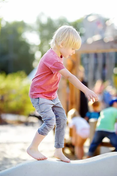 Küçük çocuk güneşli yaz gününde kamu parkı nın açık oyun alanında eğleniyor. — Stok fotoğraf