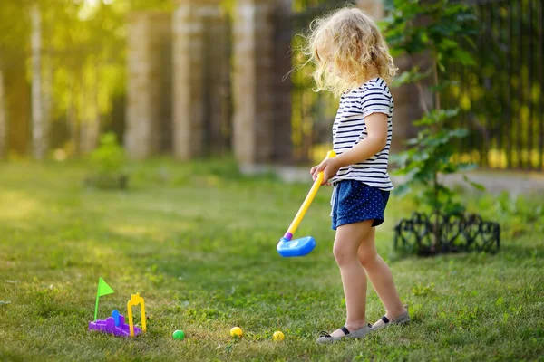 Mała dziewczynka gra w mini golfa w parku wiosennym. Dziecko bawią się z aktywnym wypoczyntem na wakacjach. — Zdjęcie stockowe