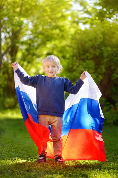 Retrato de menino bonito no parque de verão público com bandeira russa no fundo. Fãs criança apoiando e torcendo sua equipe nacional. Dia de independência . — Fotografia de Stock