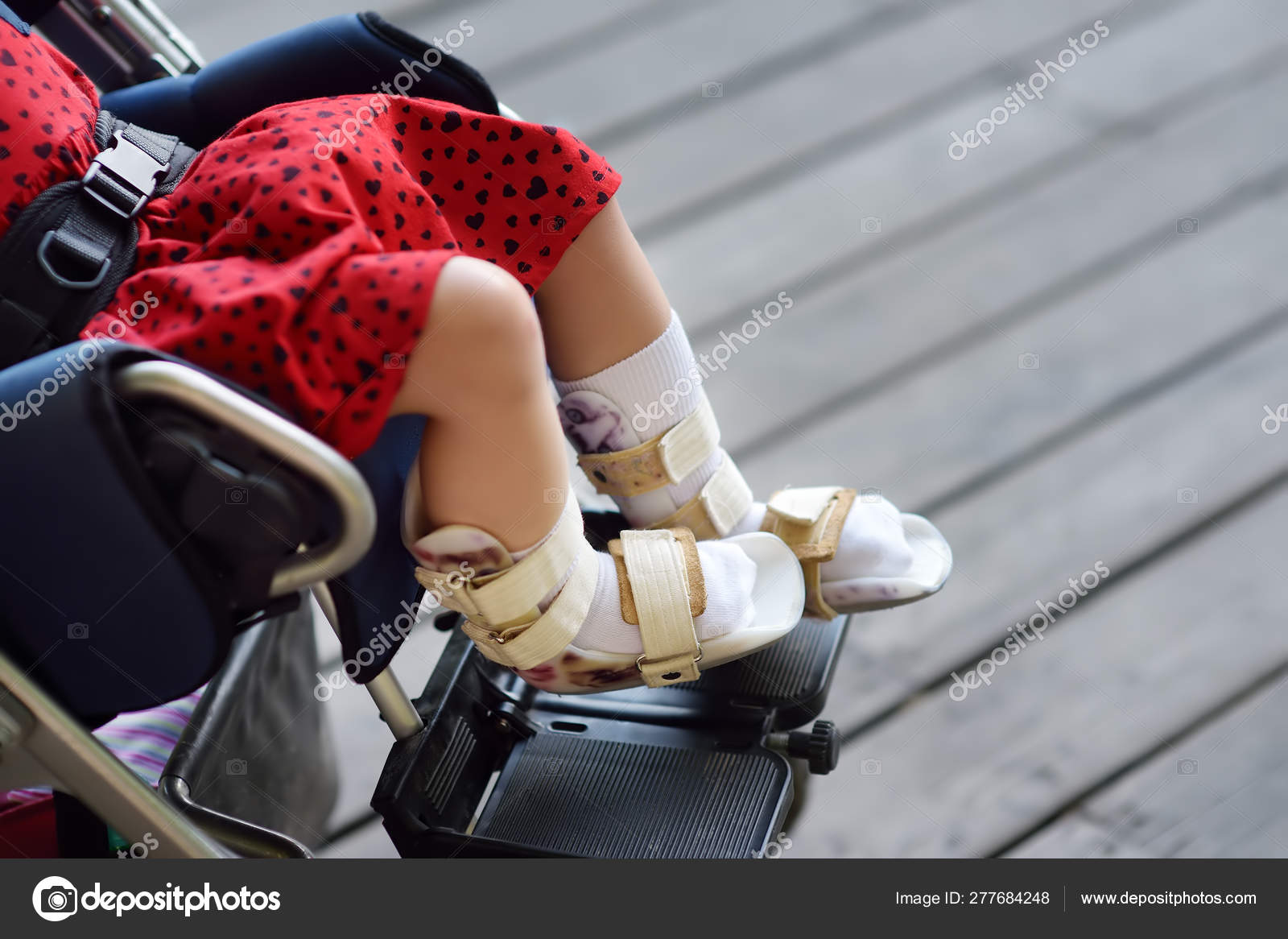 Disabled girl sitting in wheelchair. On her legs orthosis. Child ...