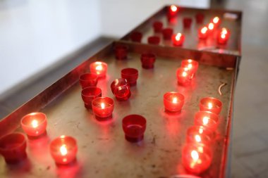 Close-up photo of church candles in red transparent chandeliers clipart