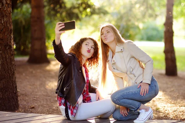 Dwie piękne młode kobiety biorą selfie na słonecznym parku. Dziewczyny. — Zdjęcie stockowe