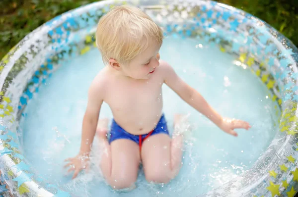 Carino bambino che nuota in una piscina gonfiabile all'aperto sul cortile nella soleggiata giornata estiva . — Foto Stock