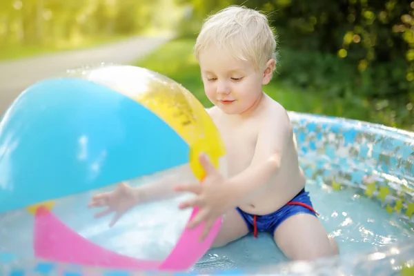 Carino bambino che nuota in una piscina gonfiabile all'aperto sul cortile nella soleggiata giornata estiva . — Foto Stock