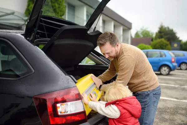 Handsome man and his little son going to vacations, loading their suitcase in car trunk. Automobile trip in the countryside. Roadtrip for family with kids — Stock Photo, Image