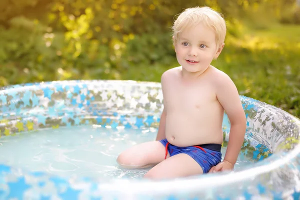 Lindo niño nadando en una piscina inflable al aire libre en el patio trasero en el día soleado del verano . —  Fotos de Stock