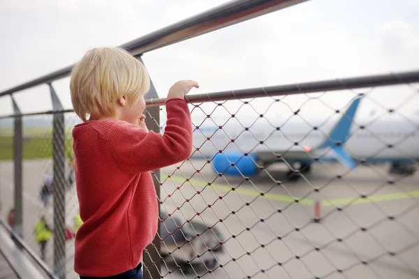 Lindo niño mirar a los aviones en la cubierta de observación en el aeropuerto de la pequeña ciudad europea antes del vuelo. Un pasajero encantador esperando el embarque. Viajes en familia con concepto infantil — Foto de Stock