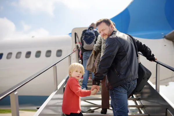El niño y su padre suben a la pasarela en el avión en el fondo de la gente pasajera. Vista trasera . — Foto de Stock