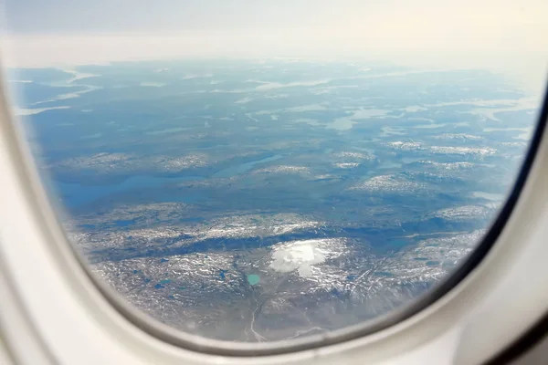 Vista la terra da finestra di aeroplano. Montagne visibili, lago, fiumi e nuvole sopra di loro. Vista ad angolo alto. Tramonto . — Foto Stock