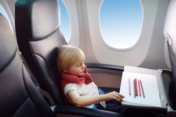 Очаровательный ребенок летит на самолёте. Радостный мальчик, сидящий у окна самолета во время полета. Детский рисунок . — стоковое фото