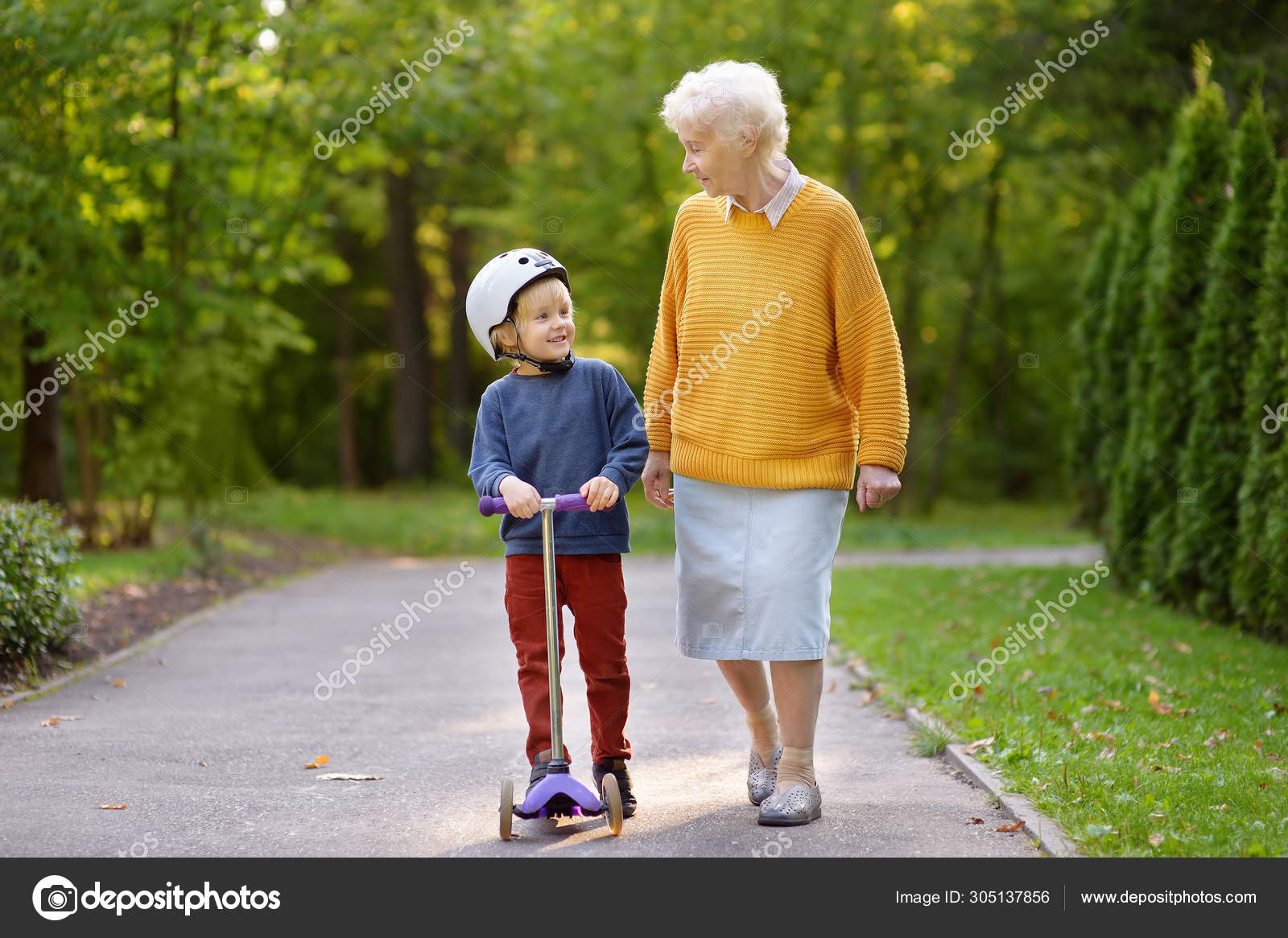 granny and boy Beautiful granny and her little grandchild walking together in autumn park.  Boy riding by scooter. — Stock Photo © mary_smn #305137856
