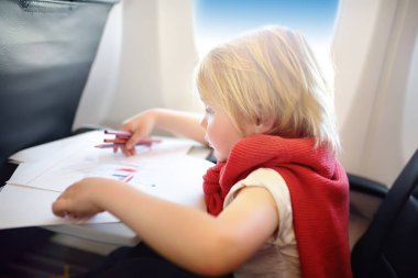 Uçakla seyahat eden sevimli çocuk. Uçuş sırasında uçak penceresinde oturan neşeli küçük çocuk. Çocuk çizim resmi.