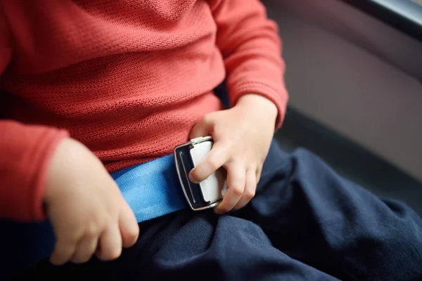 Un chico encantador viajando en un avión. El niño se abrocha el cinturón de seguridad de la silla de avión durante el vuelo. Seguridad en el transporte . —  Fotos de Stock