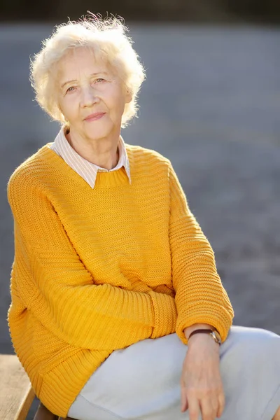 Venku portrét nádherné usměvavé starší ženy s kudrnatými bílými vlasy. Stará dáma procházka v podzimním parku. — Stock fotografie