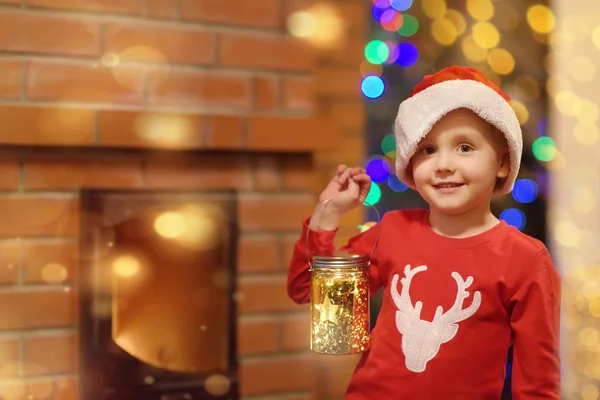 圣诞前夕，身穿圣诞礼帽和节日服装的小孩拿着装饰灯笼在家里壁炉边 — 图库照片