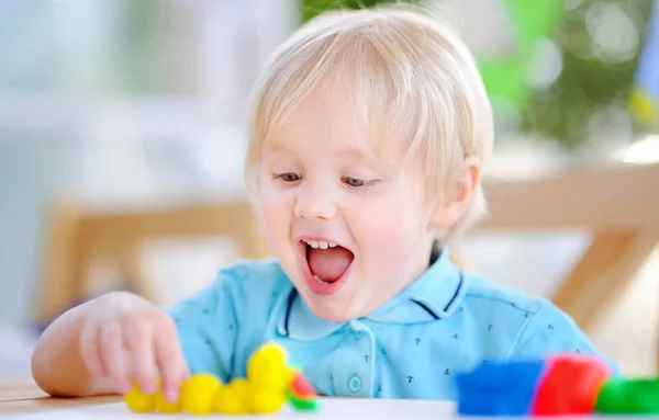 Creative boy playing with colorful modeling clay at kindergarten