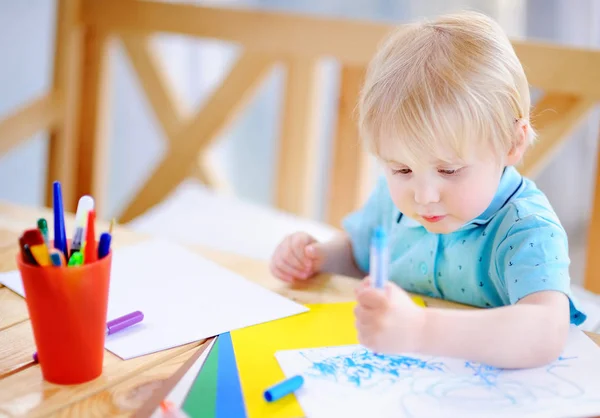 Симпатичний маленький хлопчик малює і малює барвистими маркерами ручки в дитячому саду — стокове фото