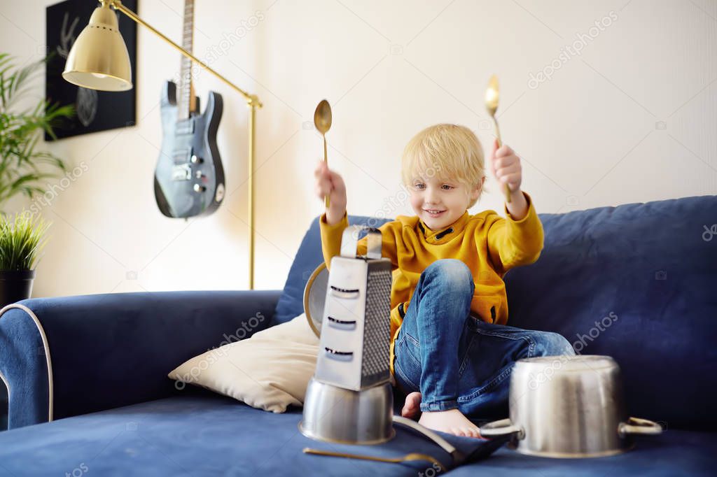 Mischievous preschooler boy play the music using kitchen tools and utensils. Funny drum part from little boy.