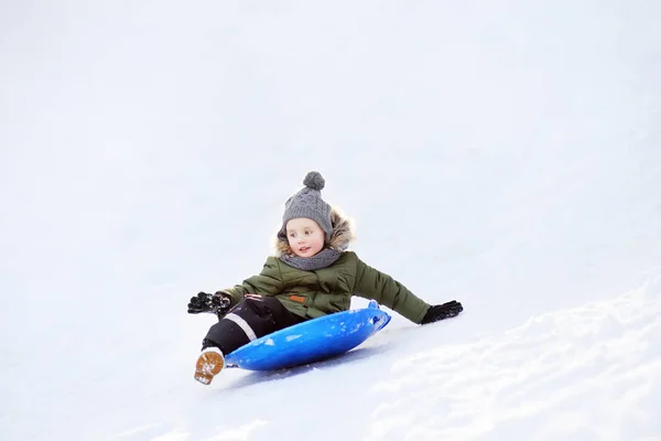 Little boy enjoy riding on ice slide in winter. — Stock Photo, Image