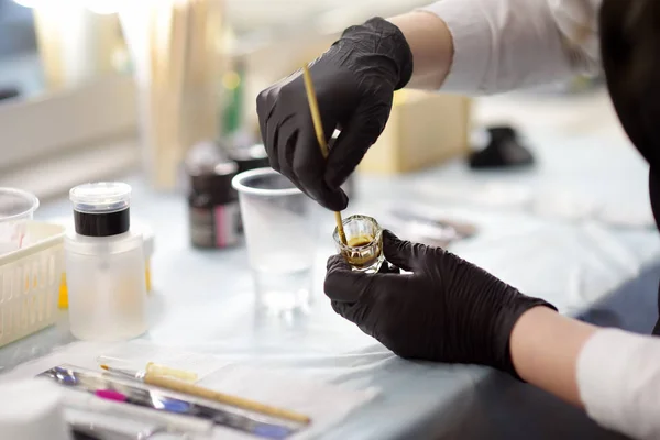 Schoonheidsspecialiste roert de kleur van de wenkbrauwen en bereidt deze voor op gebruik. Close-up zicht op handen van make-up kunstenaar. — Stockfoto