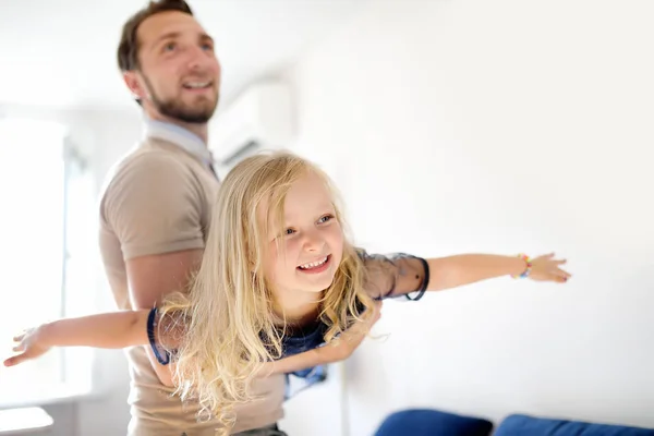 Gelukkig jong knap vader met zijn kleine krullend haar dochter spelen thuis. — Stockfoto