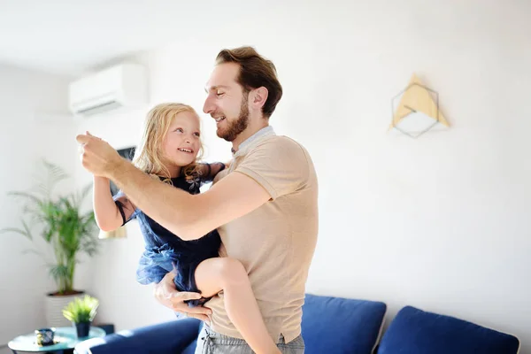 Gelukkig jonge knappe vader met zijn kleine krullend haar dochter dansen thuis. — Stockfoto