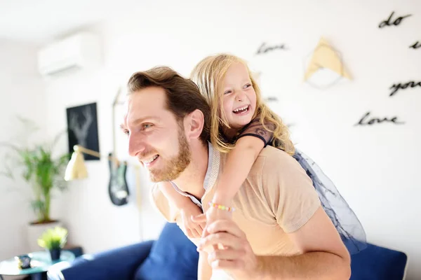 Gelukkig jong knap vader met zijn kleine krullend haar dochter spelen thuis. — Stockfoto