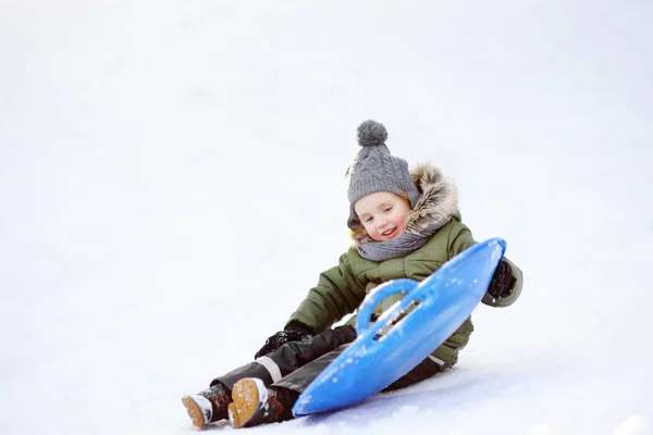 Little boy enjoy riding on ice slide in winter. — Stock Photo, Image