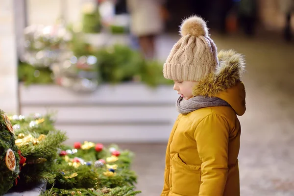 Niño pequeño eligiendo corona de Navidad en el mercado tradicional en el día de invierno en Tallin, Estonia . — Foto de Stock