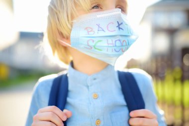 Yüz maskeli çocuk karantina ve tecritten sonra tekrar okula gidiyor. Koronavirüs salgını ve grip salgını sırasında korunma ve önleme için yeni bir normaldir. Çocuklar okul konseptine geri dönüyor.