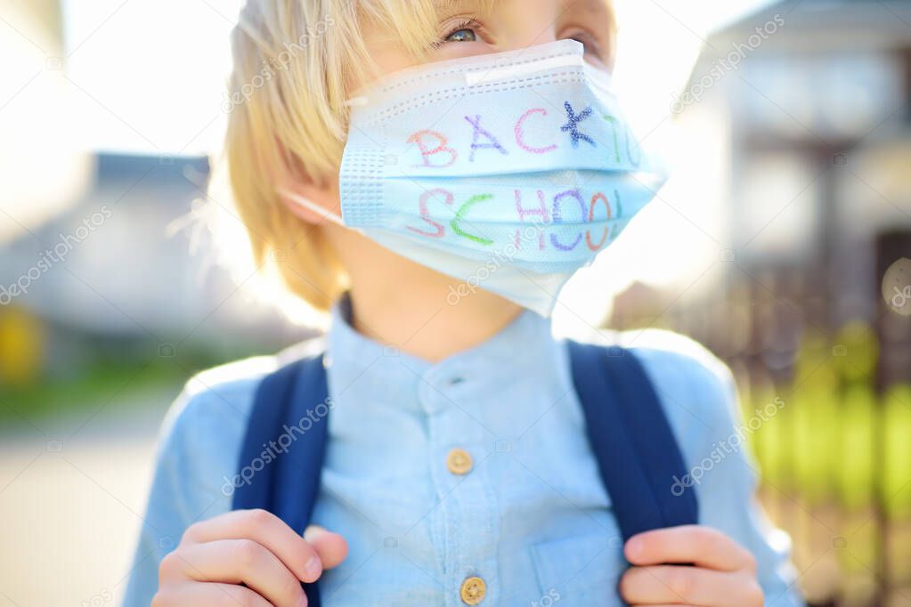 Child in face mask going at reopen school after covid-19 quarantine and lockdown. It is new normal for protection and prevention while outbreak of coronavirus or flu. Kids back to school concept.