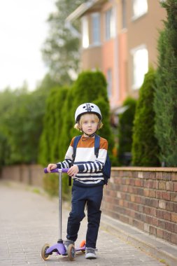 Okula scooter 'la giden kasklı küçük bir çocuk. Kalite, şehrin sokaklarındaki güvenlik çocukları için ekipmanları korur. Okula dönmek ve çocuk konsepti için eğitim.