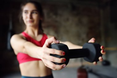 Spor yaparken dambılları kaldıran bir kız. Genç bir kadın spor yapıyor. Normal spor bağışıklık sistemini güçlendirir ve hastalıklara karşı iyi sağlık ve direnç sağlar. Sağlıklı yaşam tarzı