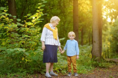 Tatlı torun, yaz parkında yürürken neşeli yaşlı büyükannesinin elini tutuyor. İki nesildir birlikte vakit geçiriyorlar. Kaliteli aile zamanı