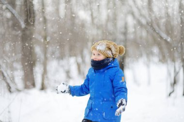 Küçük çocuk taze karla oynarken eğleniyor. Kar savaşı