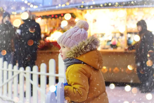 雪の中で伝統的なクリスマスフェアで彼の家族と一緒に楽しんでいる小さな男の子 冬の休日の伝統 エストニアのタリンでクリスマスマーケットの休日 — ストック写真