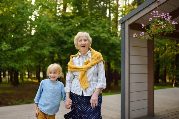Netter Enkel Hält Händchen Mit Seiner Fröhlichen Älteren Großmutter Beim — Stockfoto
