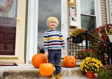 Çocuk şeker mi şaka mı için hazır. Cadılar Bayramı partisindeki küçük çocuk. Çocuk kutlaması Cadılar Bayramı. Geleneksel tatil Bir kova şeker ve şekerle