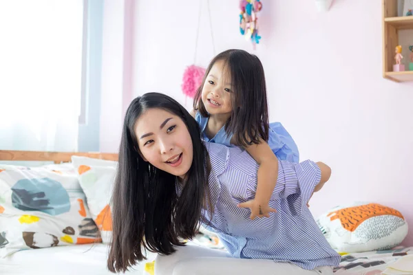 一个快乐的亚洲小女孩在她妈妈身后的房子里 — 图库照片