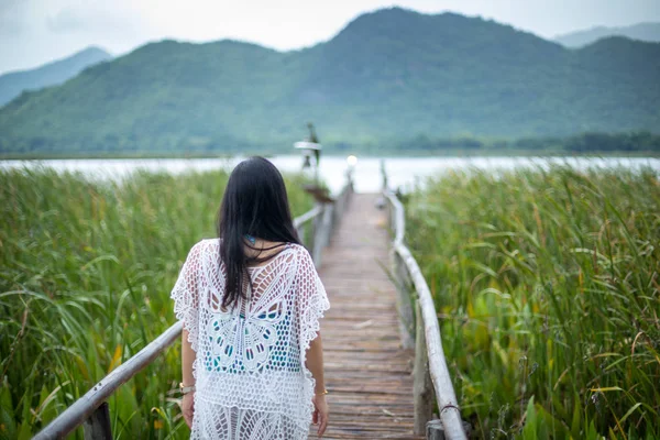 Young woman stands on a wooden bridge on the nature background