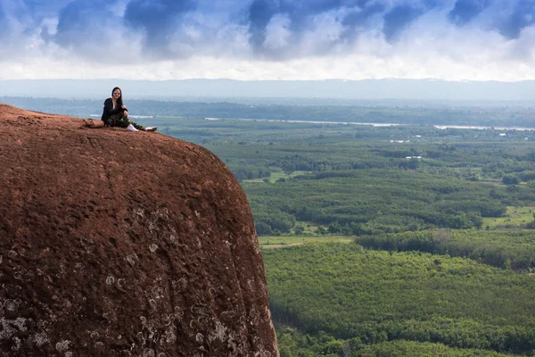 Jonge vrouw zittend op een berg top — Stockfoto