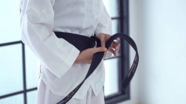 Genç Asyalı kız stüdyoda siyah kuşak düğümlüyor.