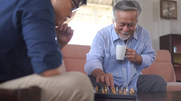 亚洲老年人在家里和儿子下棋 — 图库照片