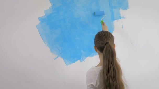Young girl paints the wallpaper with a roller in the room with blue paint — Stock Footage Young girl paints the wallpaper with a roller in the room with blue paint Stock Video