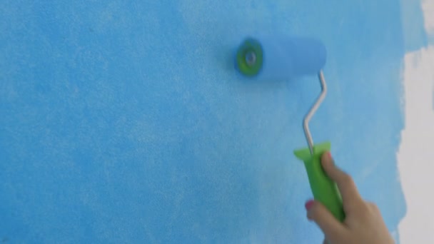 Young girl paints the wallpaper with a roller in the room with blue paint — Stock Footage Young girl paints the wallpaper with a roller in the room with blue paint Royalty Free Stock Footage