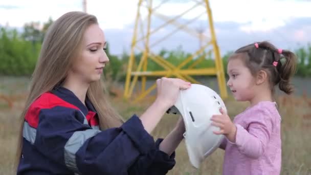 Ein kleines Mädchen setzt einem Techniker einen Helm für seine Mutter auf. Sorge um zukünftige Generationen und die Umwelt