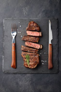 Closeup biftek new York sığır ırkları kara Angus otlar, sarımsak ve bir taş tahta üzerine tereyağı ile yemeye hazır. Bitmiş çanak taş karanlık bir arka plan akşam yemeği için. Üstten Görünüm.