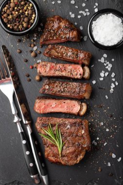 Closeup biftek new York sığır ırkları kara Angus otlar, sarımsak ve bir taş tahta üzerine tereyağı ile yemeye hazır. Bitmiş çanak taş karanlık bir arka plan akşam yemeği için. Üstten Görünüm.